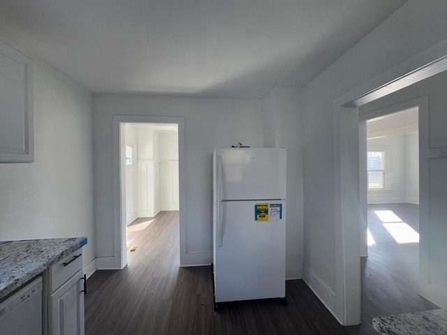 kitchen featuring white cabinets, light stone countertops, white appliances, and dark wood-type flooring