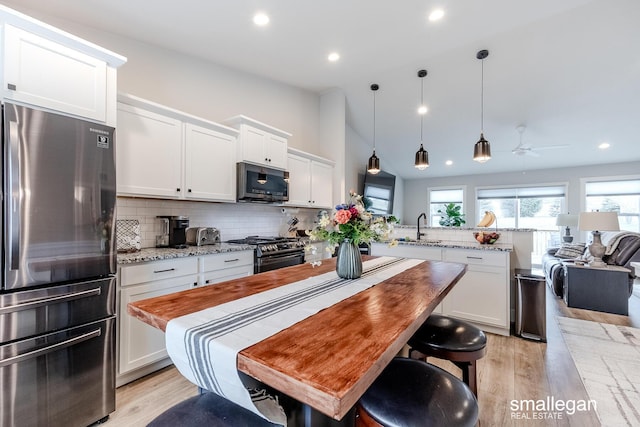 kitchen featuring kitchen peninsula, light stone counters, white cabinets, and stainless steel appliances