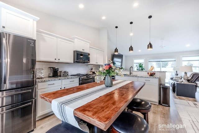 kitchen with tasteful backsplash, a peninsula, stainless steel appliances, white cabinetry, and a sink