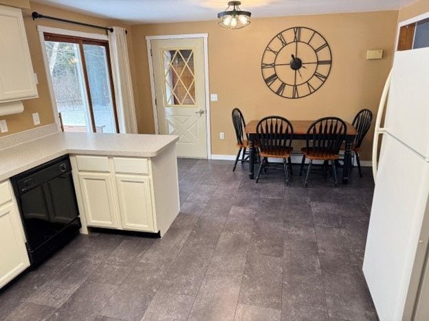 kitchen with dishwasher, light countertops, freestanding refrigerator, and white cabinets