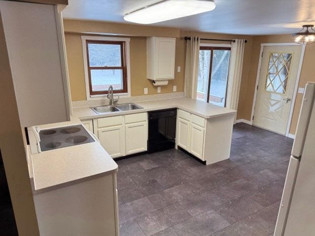 kitchen with light countertops, white cabinetry, a sink, dishwasher, and a peninsula