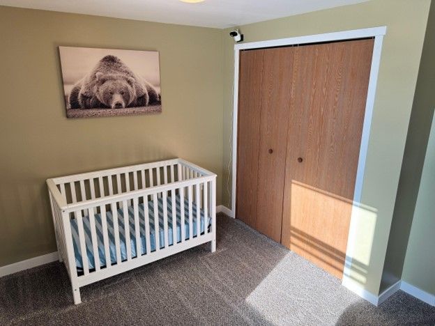 carpeted bedroom featuring a nursery area, a closet, and baseboards