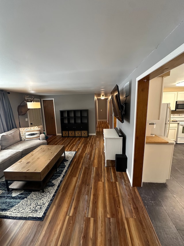 living room with dark wood-style floors, baseboards, and stairway