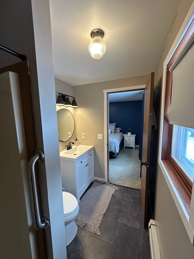 ensuite bathroom with ensuite bathroom, toilet, a baseboard heating unit, vanity, and baseboards