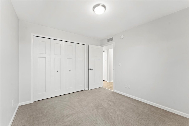 unfurnished bedroom with light carpet and a closet