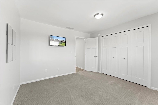 unfurnished bedroom with light carpet and a closet