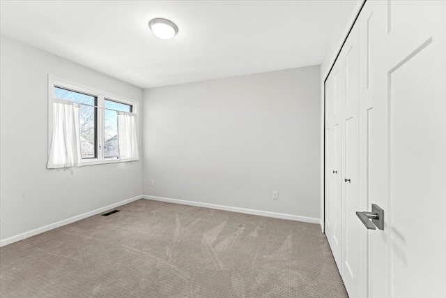 unfurnished bedroom featuring a closet and light colored carpet