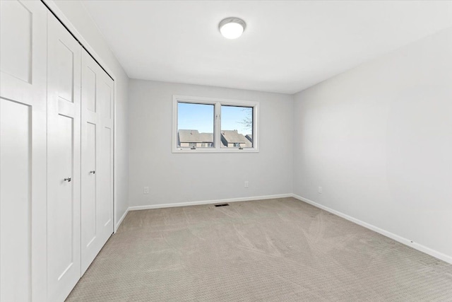 unfurnished bedroom featuring light carpet and a closet