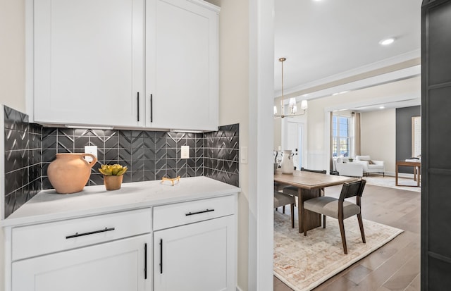 kitchen with white cabinetry, ornamental molding, dark hardwood / wood-style floors, pendant lighting, and decorative backsplash