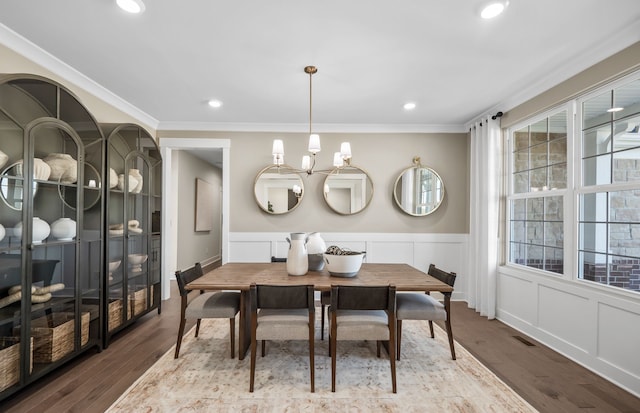 dining space featuring hardwood / wood-style floors, crown molding, a wealth of natural light, and a chandelier