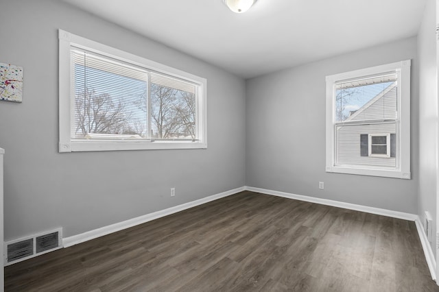unfurnished room with dark hardwood / wood-style flooring and a healthy amount of sunlight