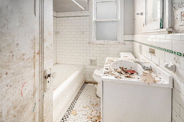 bathroom with vanity, a tub, tile walls, and toilet