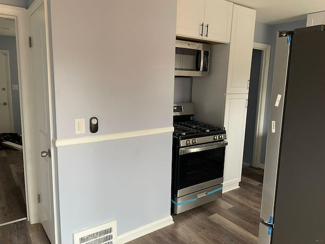 kitchen featuring dark hardwood / wood-style flooring, white cabinetry, and appliances with stainless steel finishes