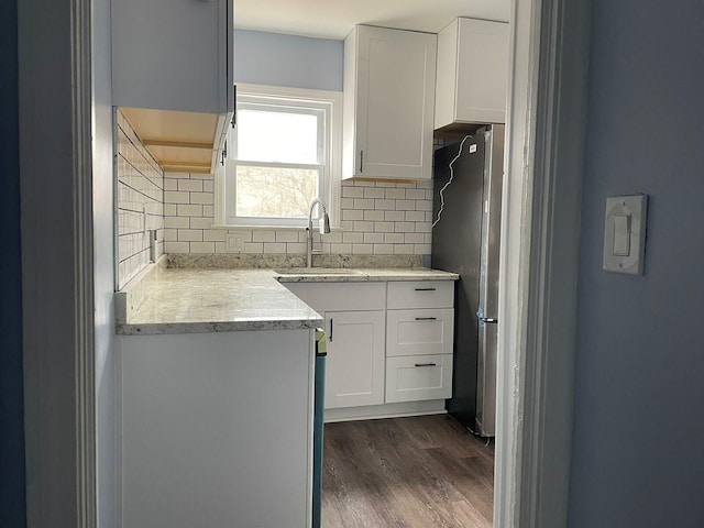 kitchen with tasteful backsplash, stainless steel fridge, sink, and white cabinets