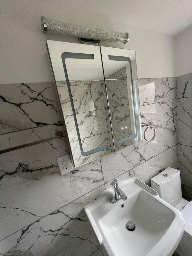 bathroom featuring sink, tile walls, and toilet