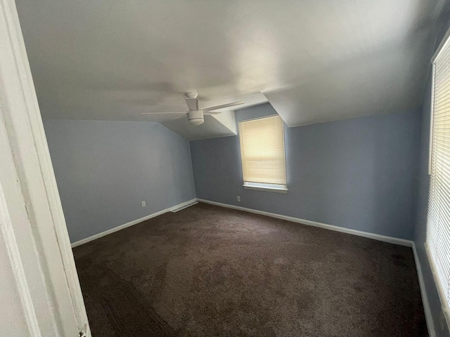 additional living space featuring dark carpet, vaulted ceiling, and ceiling fan