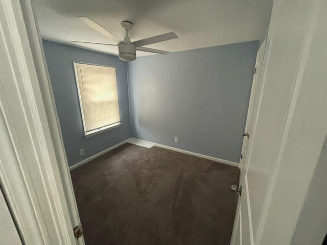 empty room with ceiling fan and dark carpet