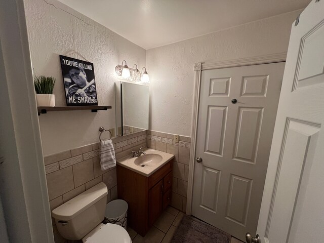 bathroom with tile walls, vanity, tile patterned floors, and toilet