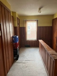 hall with wooden walls and light colored carpet