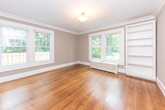 unfurnished room featuring hardwood / wood-style flooring, plenty of natural light, ornamental molding, and radiator