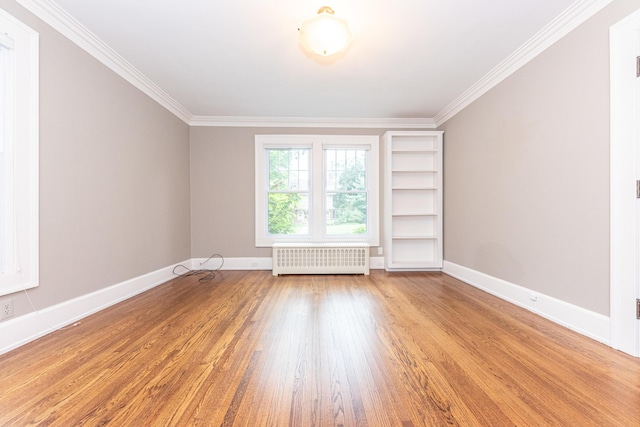 empty room featuring light wood-type flooring, built in features, ornamental molding, and radiator