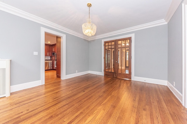 empty room with crown molding, a chandelier, and wood-type flooring