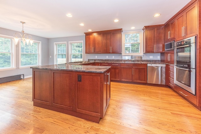 kitchen with hanging light fixtures, a chandelier, dark stone counters, a kitchen island, and appliances with stainless steel finishes