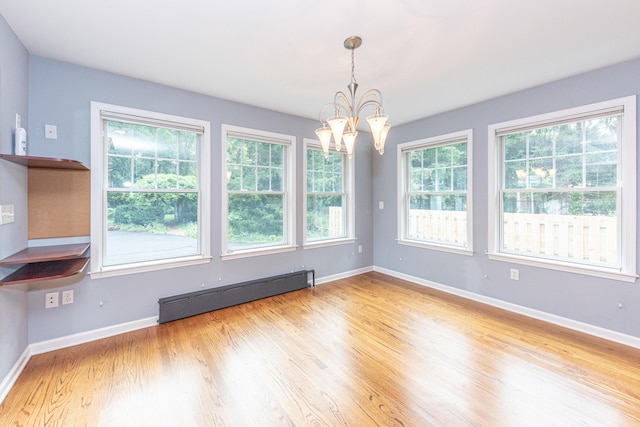 unfurnished dining area featuring a chandelier, light wood-type flooring, and a baseboard heating unit