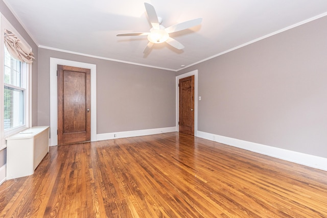 empty room with ceiling fan, ornamental molding, a healthy amount of sunlight, and wood-type flooring