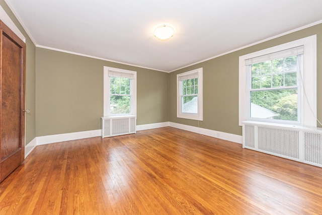 empty room with radiator heating unit, hardwood / wood-style flooring, and a wealth of natural light