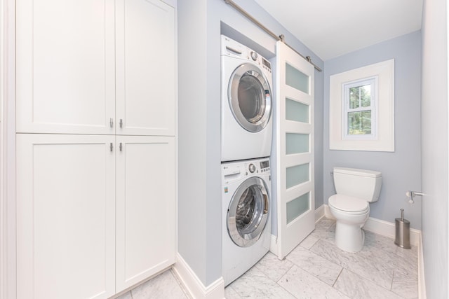 clothes washing area featuring a barn door and stacked washer and clothes dryer