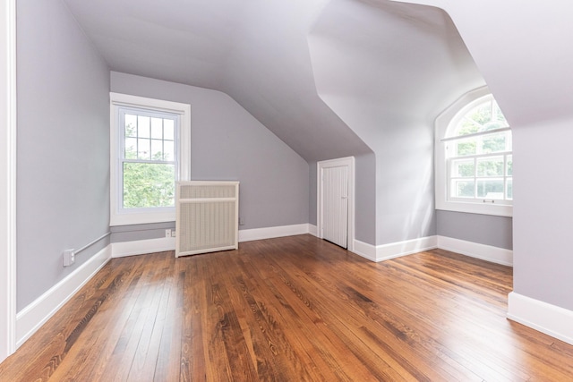 bonus room with radiator heating unit, dark wood-type flooring, and vaulted ceiling