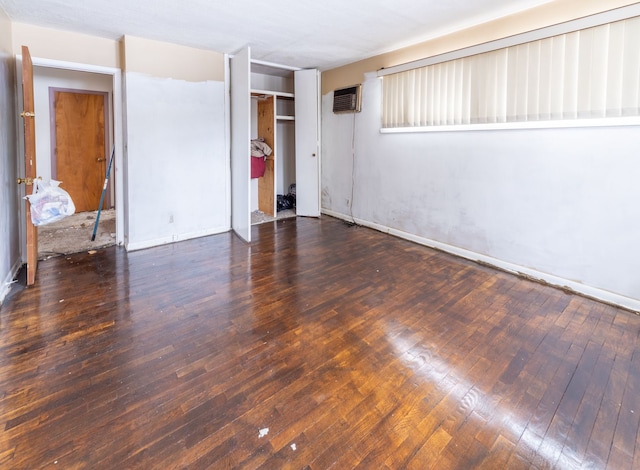 unfurnished room featuring a wall mounted air conditioner and dark hardwood / wood-style flooring