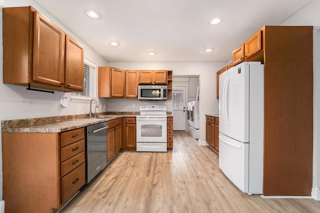 kitchen with separate washer and dryer, sink, light wood-type flooring, and appliances with stainless steel finishes