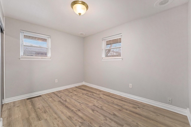 empty room with hardwood / wood-style floors and a healthy amount of sunlight