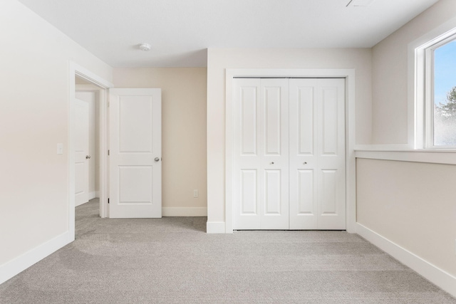 unfurnished bedroom with light colored carpet and a closet