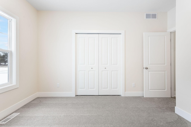 unfurnished bedroom featuring a closet, light colored carpet, and multiple windows