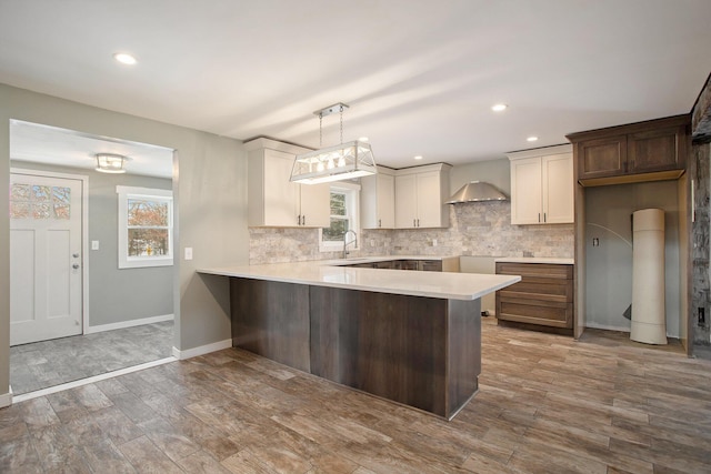 kitchen featuring wall chimney exhaust hood, dark hardwood / wood-style floors, plenty of natural light, decorative light fixtures, and white cabinets