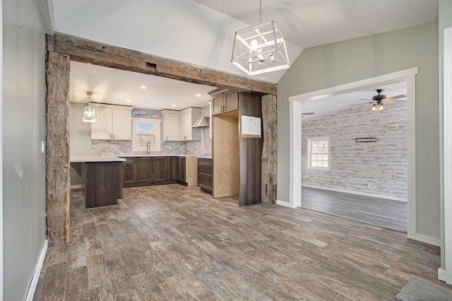 kitchen featuring lofted ceiling, white cabinets, sink, decorative backsplash, and ceiling fan