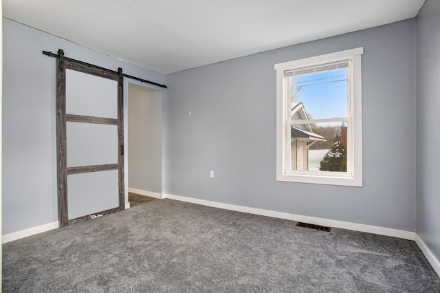 unfurnished bedroom featuring a barn door and carpet floors