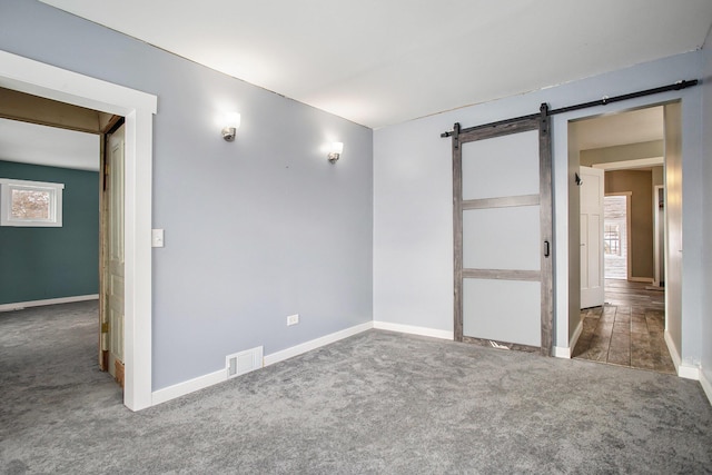 carpeted empty room with a barn door and a wealth of natural light