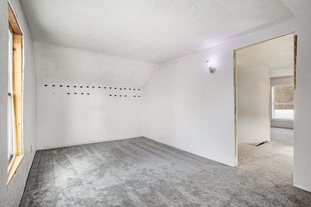 carpeted empty room with lofted ceiling and a textured ceiling