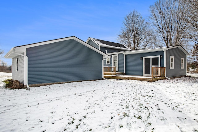 snow covered back of property featuring a deck