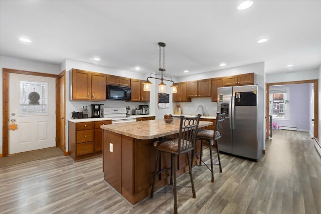 kitchen with electric stove, pendant lighting, a center island, stainless steel fridge, and wood-type flooring