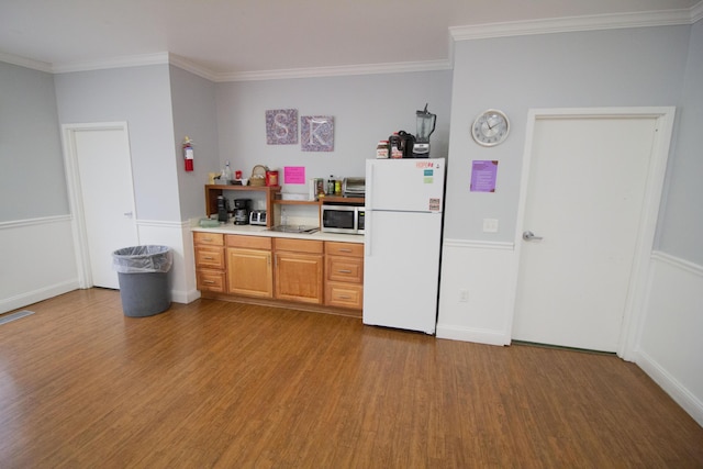 kitchen with wood-type flooring, white fridge, and ornamental molding