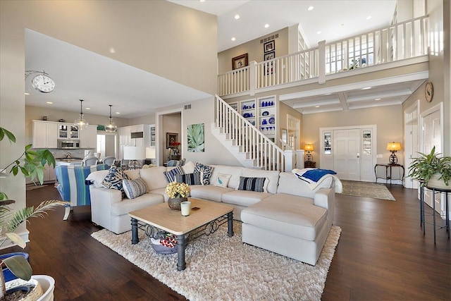 living room with beam ceiling, dark hardwood / wood-style flooring, coffered ceiling, and a high ceiling