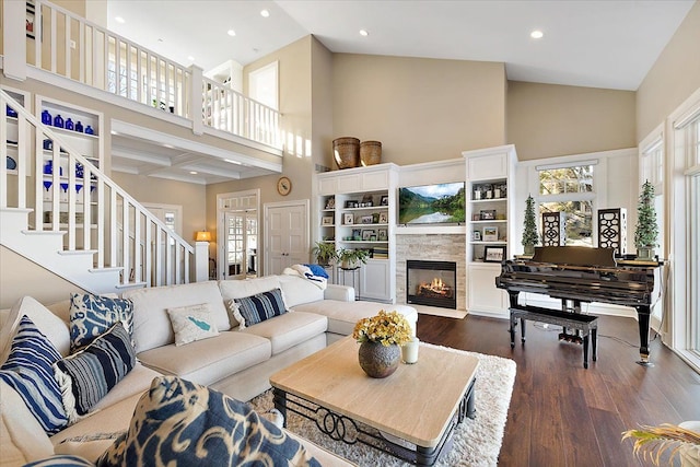 living room featuring beamed ceiling, dark hardwood / wood-style flooring, a towering ceiling, and a fireplace