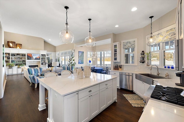 kitchen with a kitchen bar, light stone countertops, stainless steel dishwasher, white cabinets, and a center island