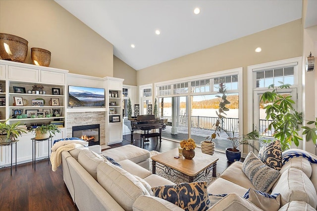 living room with dark hardwood / wood-style floors, a stone fireplace, and high vaulted ceiling