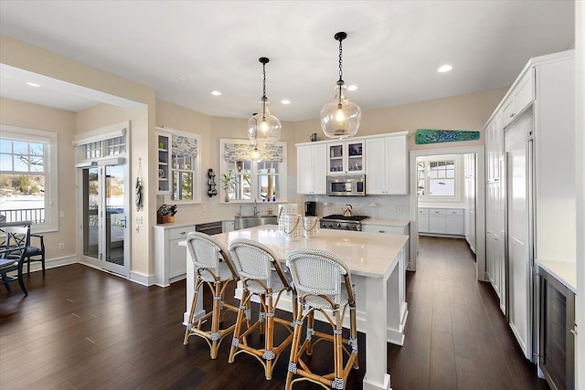 kitchen featuring a center island, backsplash, white cabinets, sink, and decorative light fixtures